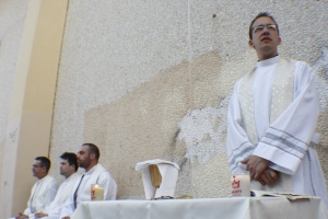 Fr.  John Putzer stands behind the makeshift altar at the sports center in Velillas de San Antonio.